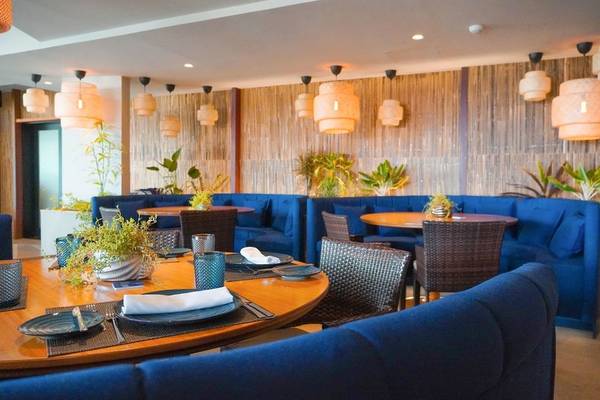 Innenbereich des Calheta Beach Hotels mit blauen Sofas, runden Tischen und hängenden Laternen.