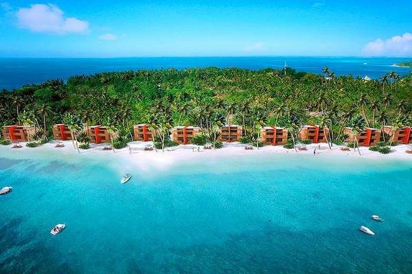 Außenansicht des Barefoot Eco Hotels auf einer Insel mit mehreren roten Gebäuden und grünen Palmen.