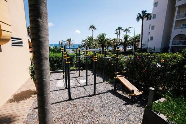 Fitnessbereich im Freien vor dem Views Oasis Hotel mit Geräten und Meerblick.
