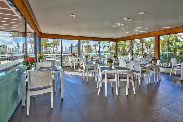 Innenansicht des The Views Oasis Hotel Restaurants mit großen Fenstern und Meeresblick.
