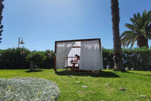 Massagezelt im Freien des Views Oasis Hotel unter Palmen und Büschen.
