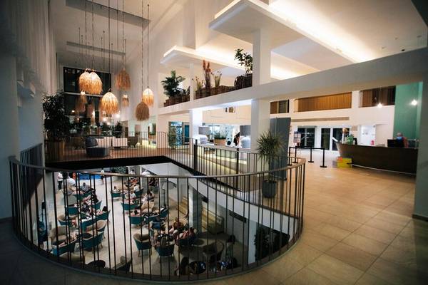 Innenansicht der Lobby des Views Oasis Hotel mit mehreren Gästen, Tischen, Stühlen und Pflanzen.
