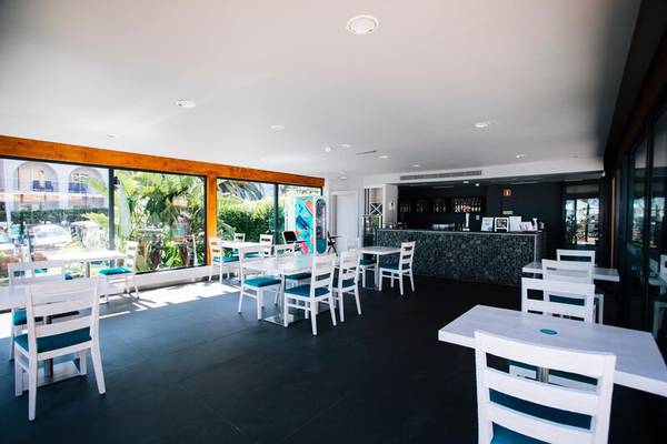 Innenansicht des The Views Oasis Hotel Restaurants mit weißen Tischen und Stühlen und großen Fenstern.