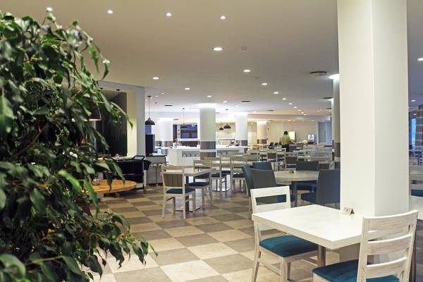 Innenbereich des Restaurants im Views Oasis Hotel mit weißen Tischen und Stühlen, beleuchteten Säulen und gemustertem Boden.