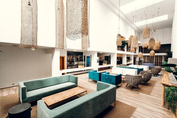 Lobby des Views Oasis Hotels mit modernen Möbeln, Holzböden und hängenden Lampen.