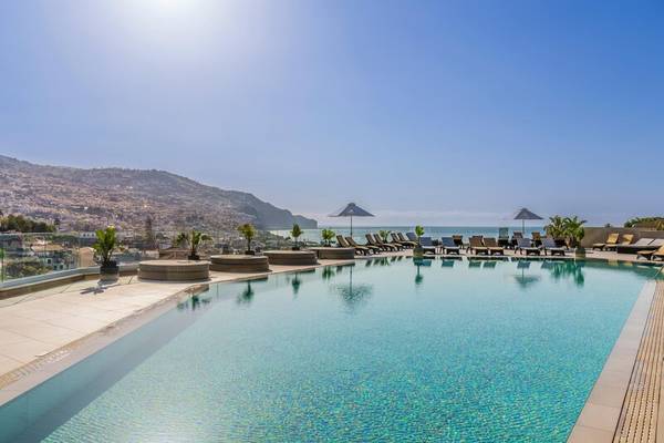 Obere Ansicht des Pools im The Views Baia Hotel mit Sonnenliegen und Blick auf das Meer und die Stadt.