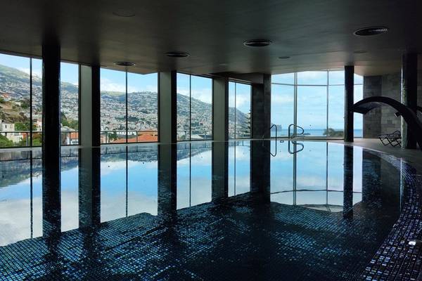Innenansicht des Schwimmbeckens im Views Baia Hotel mit großen Fenstern und Meerblick.