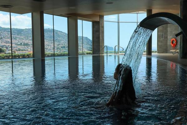 Frau schwimmt im Innenpool des Views Baia Hotels mit Blick auf die Stadt und Berge