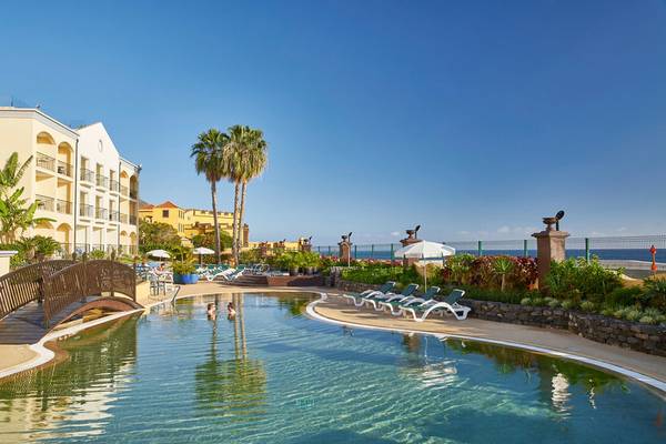 Außenansicht des Pools des Porto Santa Maria Hotels mit Lounge-Stühlen und Sonnenschirmen.