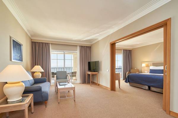 Innenansicht einer Suite im Hotel Porto Santa Maria mit Wohnzimmer, Schlafbereich und Balkon