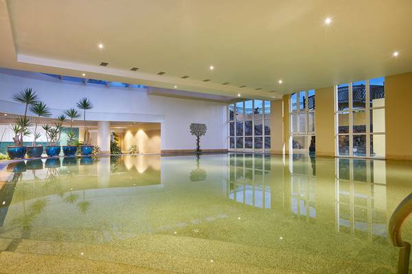 Innenpool des Porto Santa Maria Hotels mit blauen Pflanzen und großen Fenstern