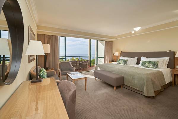 Hotelzimmer im Cliff Bay mit Meerblick, großem Bett, Balkon und moderner Einrichtung.