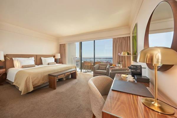 Hotelzimmer im Cliff Bay mit Balkon, Bett, Schreibtisch und Panoramablick auf das Meer.
