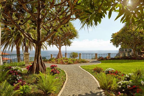 Garten von The Cliff Bay Hotel mit Blick auf das Meer und blühenden Pflanzen.