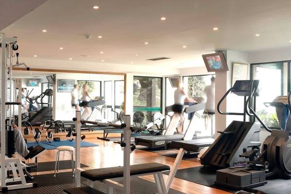 Fitnessbereich im The Cliff Bay Hotel mit verschiedenen Geräten und Menschen, die trainieren.