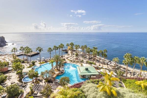 Luftaufnahme des Swimmingpools des Royal Savoy Hotels mit Blick auf das Meer und Palmen