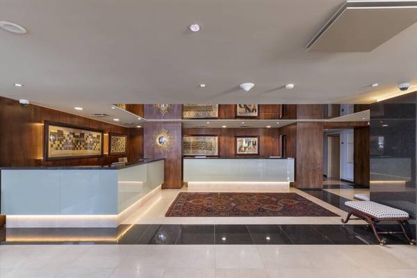 Empfangsbereich des Royal Savoy Hotels mit gemustertem Teppich und holzvertäfelten Wänden.