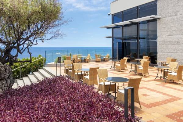Außenbereich des Royal Savoy Hotels mit Blick auf das Meer und terrassenförmigen Sitzbereichen.