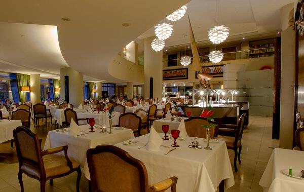 Innenansicht des Restaurants im Royal Savoy Hotel mit gedeckten Tischen und Stühlen.