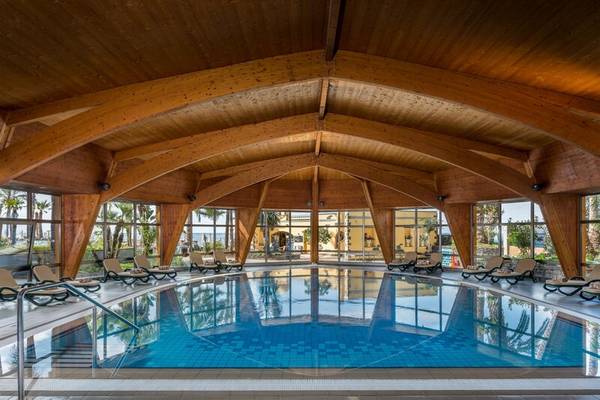 Innenpool des Royal Savoy Hotels mit blauem Wasser und hölzerner Dachkonstruktion.