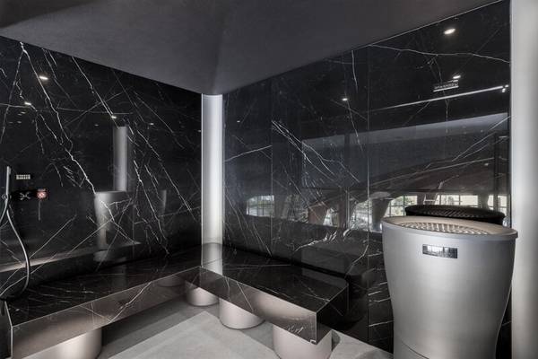 Saunabereich im Royal Savoy Hotel mit schwarzen Marmorwänden und einer modernen Bank.