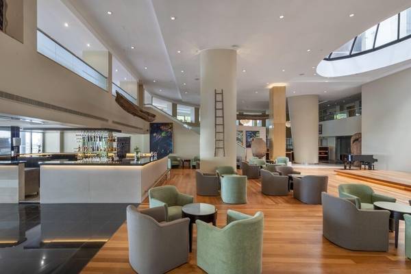 Das elegante Interieur des Royal Savoy Hotels mit Holzboden, moderner Beleuchtung und runden Möbeln.