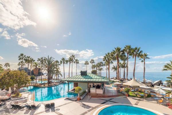 Außenbereich des Royal Savoy Hotels mit Swimmingpool und Sonnenliegen.