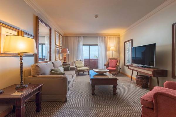 Wohnzimmer im Royal Savoy Hotel mit Sofa, Fernseher und Tischlampen.
