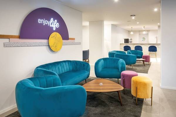 Lobby-Lounge des Allegro Madeira Hotels mit blauen Möbeln und einer leuchtenden Wanddekoration.
