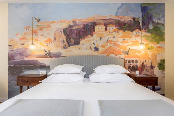 Schlafzimmer im Pestana Churchill Bay Hotel mit einem großen Wandgemälde, zwei Nachttischen und einem Bett mit weißen Kissen.