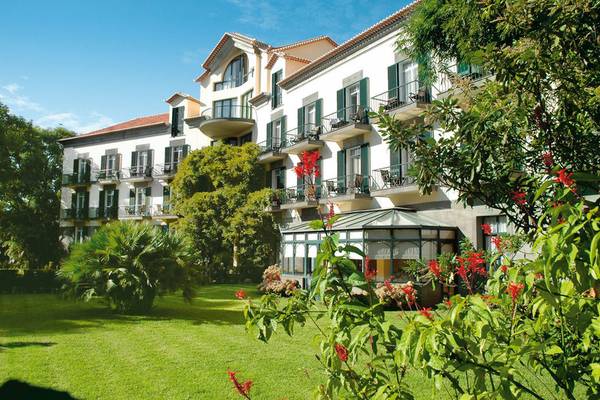 Außenansicht des Quinta da Bela Vista Hotels mit grünen Fensterläden und üppiger Gartenanlage.