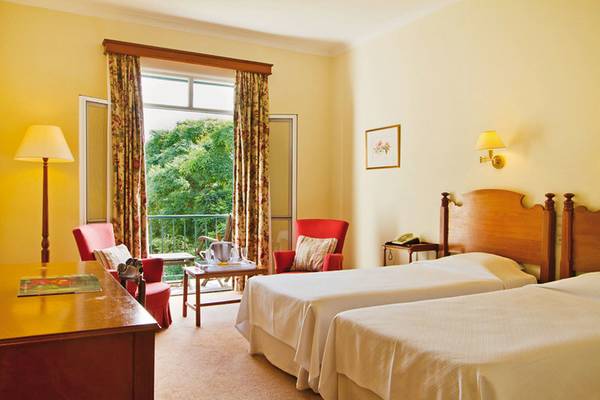 Doppelzimmer mit Balkon im Hotel Quinta da Bela Vista, mit zwei Betten, Schreibtisch und einem Tisch mit einem Glas und einer Flasche.