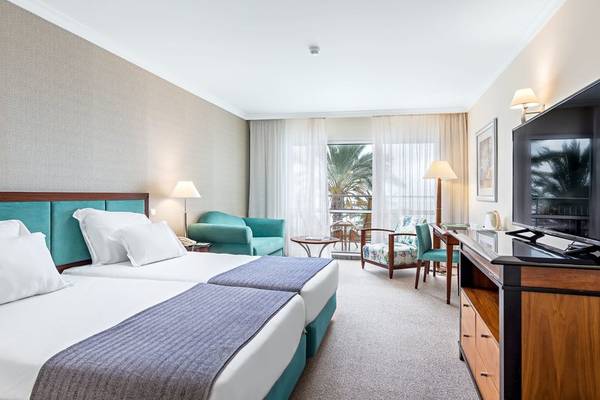 Doppelzimmer im Pestana Grand Premium Ocean Resort mit zwei Betten, einem Sofa und einem Fernseher.