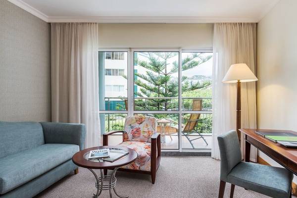 Innenansicht eines Zimmers im Pestana Grand Premium Ocean Resort mit Möbeln und Balkon.