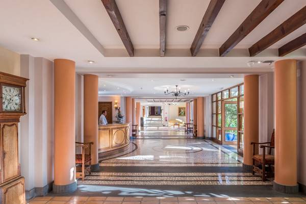 Empfangshalle des Pestana Miramar Garden & Ocean Resorts mit Rezeption, Uhr, Säulen und Sonnenlicht.