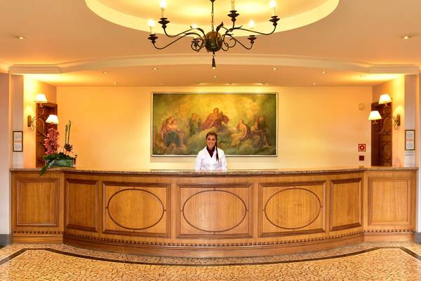 Rezeption im Pestana Miramar Garden & Ocean Resort mit einer Dame, die vor einem großen Gemälde steht.
