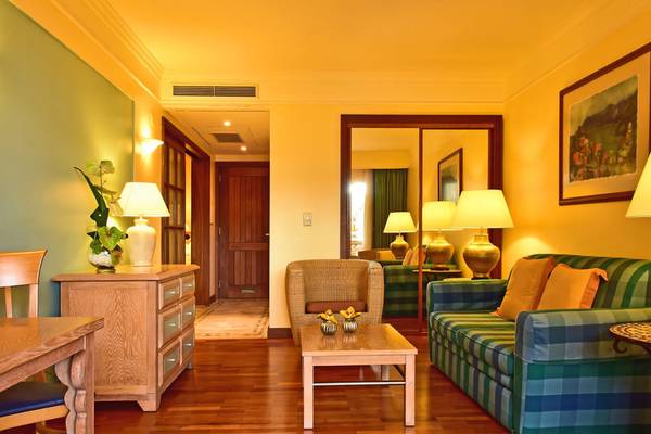 Wohnzimmer im Pestana Miramar Garden & Ocean Resort mit gemusterter Couch, Tisch und Lampen.