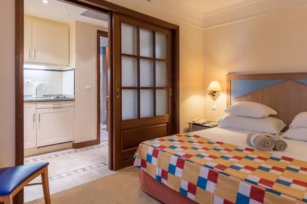 Schlafzimmer im Pestana Miramar Garden & Ocean Resort mit Doppelbett, Nachttisch, Lampe und offenem Badezimmer