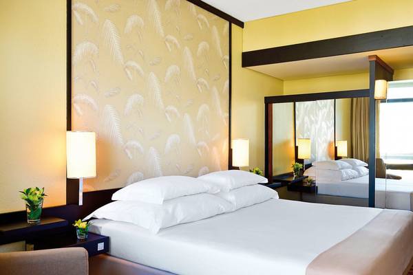 Ein Hotelzimmer im Pestana Casino Park Hotel mit zwei Betten, einem Nachttisch und Palmblatt-Tapete.