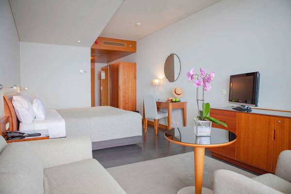 Innenansicht eines Zimmers im VidaMar Resort Hotel Madeira mit Bett, Schreibtisch und Fernseher.