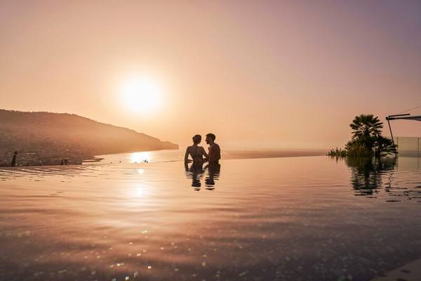 Ein Paar genießt den Sonnenuntergang im Infinity-Pool des Savoy Palace.