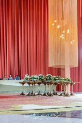 Empfangsbereich des Savoy Palace Hotels mit roten Vorhängen, goldenen Lampen und Blumen auf Tischen.
