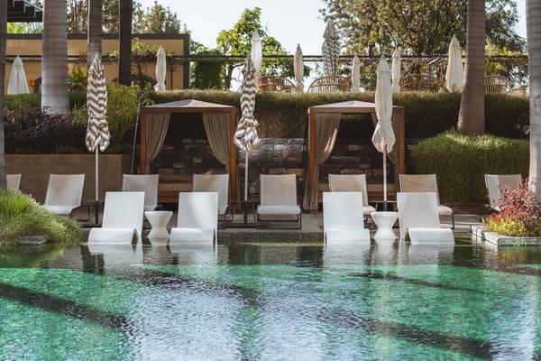 Pool-Lounge-Bereich im Savoy Palace Hotel mit weißen Liegestühlen und Sonnenschirmen.