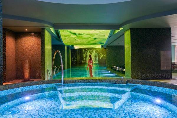 Poolbereich im Savoy Palace Hotel mit grüner Beleuchtung und Frau im roten Bikini