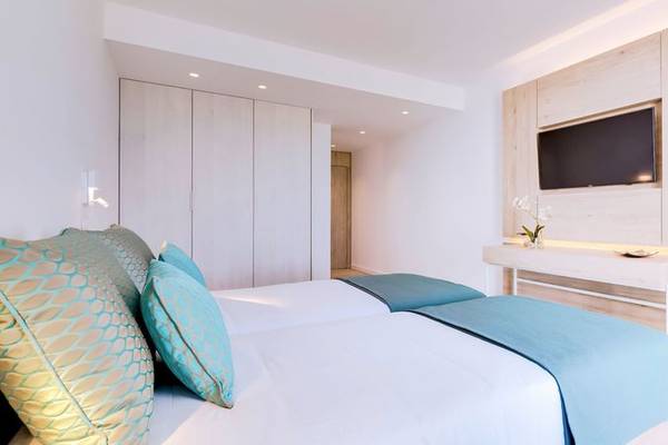 Zweibettzimmer im Sol e Mar Hotel mit weißen Wänden, blauen Bettdecken und heller Holzwand.
