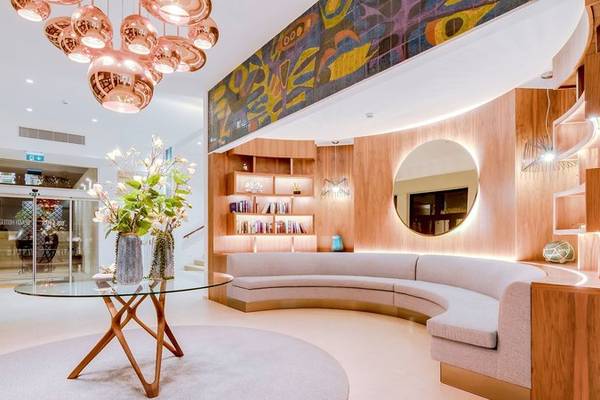 Lobby des Sol e Mar Hotels mit runden Tisch, Blumenvase, ovalem Spiegel und holzvertäfelten Wänden