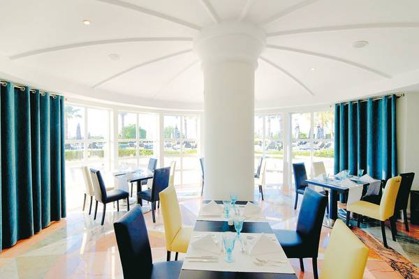 Innenansicht des Restaurants im Vila Galé Cerro Alagoa Hotel mit blauen Vorhängen und großen Fenstern.