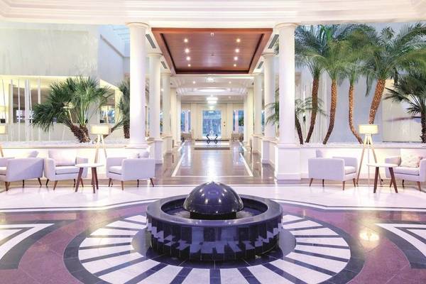 Lobby des Falesia Hotels in Algarve mit einer großen Wasserfontäne und weißen Möbeln.