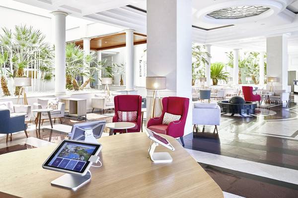 Innenbereich des Falesia Hotel - Algarve mit Rezeption, Tischen, Stühlen und Pflanzen.