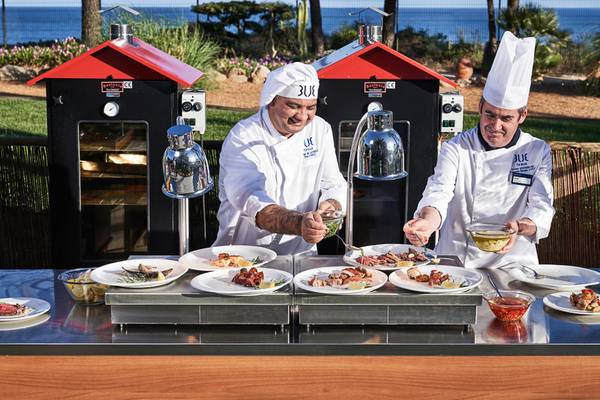 Zwei Küchenchefs am Grill im Falesia Hotel Algarve, servieren Gerichte.